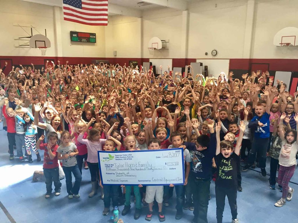 School sparrow club gathers in gym to award giant check to Horn family for over $15,000.