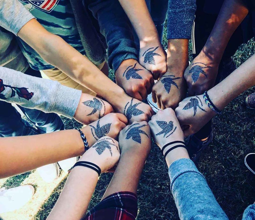 Looking down on hands with sparrow club temporary tattoos fist bumping.