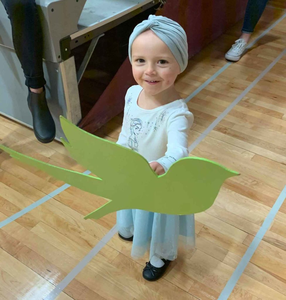 A sparrow child smiles while holding the sparrow logo.