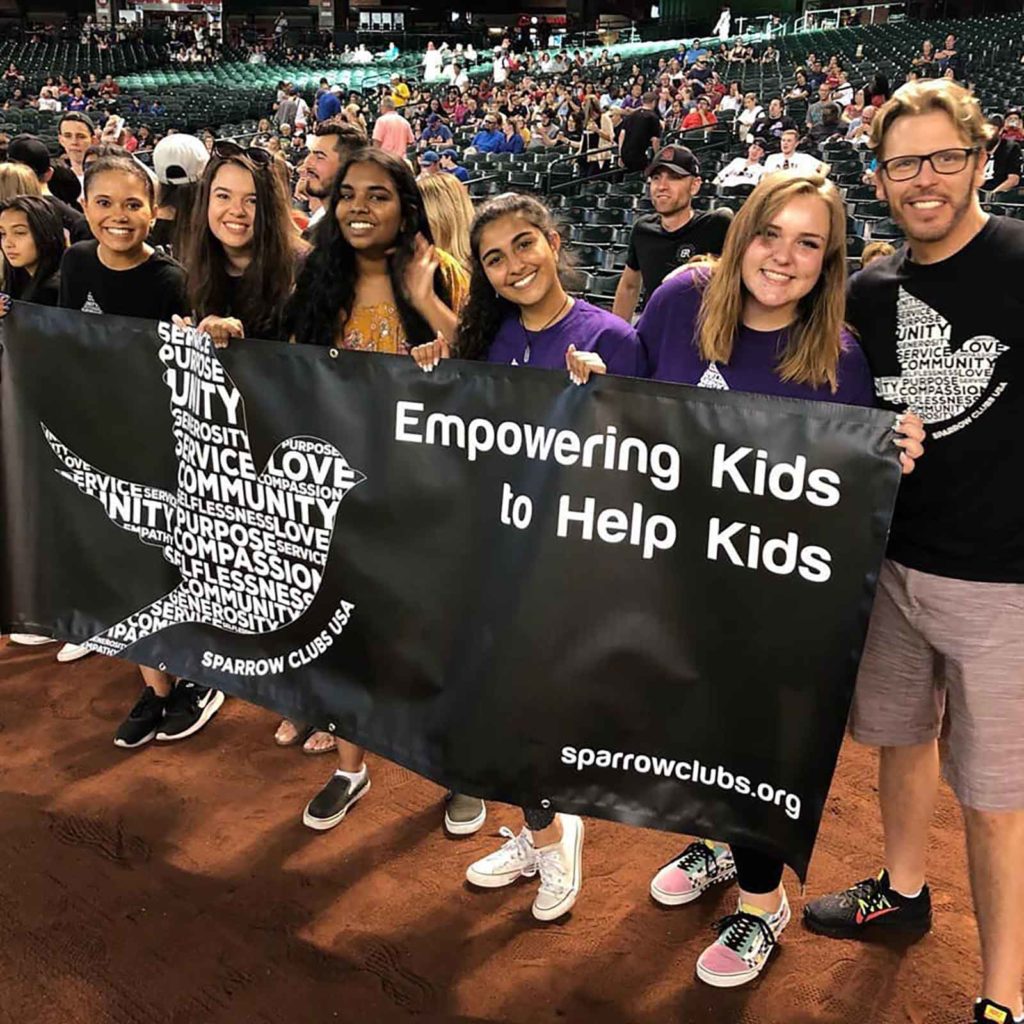 Friends hold sparrow clubs banner at event